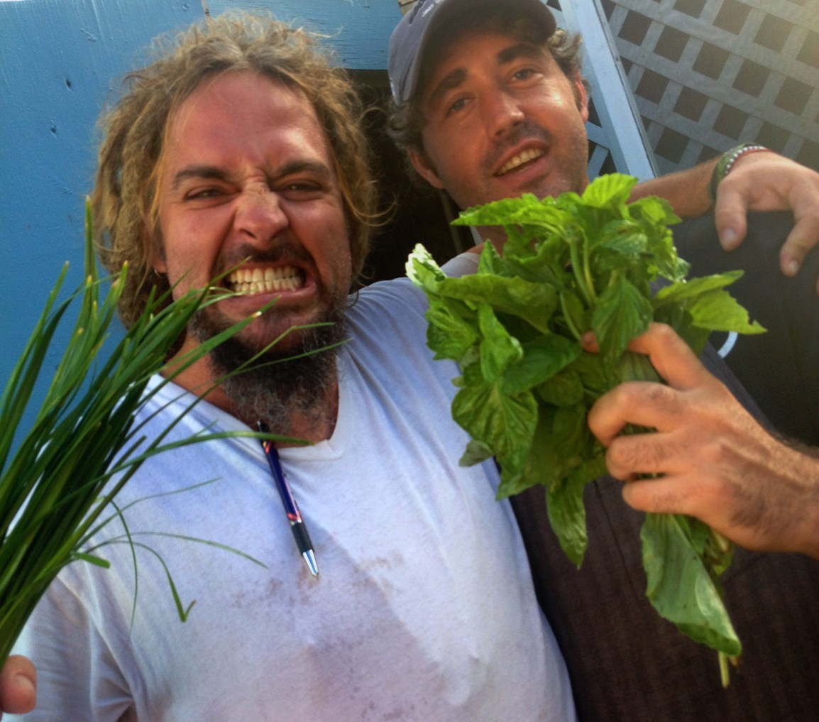 Two chefs making pirate faces hold up bunches of fresh green herbs from ARTfarm at Savant Restaurant in Christiansted, St. Croix USVI.