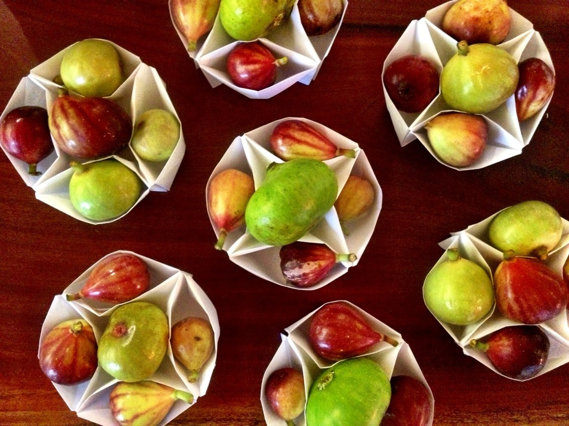 Origami paper baskets hold five luscious fresh figs each, in brilliant jewel-like shades of green and red and various sizes and shapes.