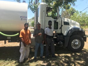 Three equipment operators with a new tanker truck.